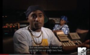 Tupac in a white shirt, gold chains -- The hip hop Debate