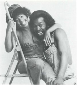 Nick Ashford & Valerie Simpson hugging eachother; Valerie sits on a ladder