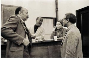 Top: Felrath Hines, Norman and Ouida Lewis, Ernest Crichlow at Cinque Gallery, c. 1970−73. © ChesterHiggins/chesterhiggins.com Left: Ernest Crichlow, Ruth Jett with Cinque Gallery friends, c. 1990s Right: Ernest Crichlow, Romare Bearden, Herbert Gentry and family at Cinque Gallery, c. 1970−73. © ChesterHiggins/chesterhiggins.com