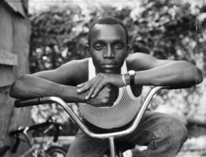 Dawoud Bey, A Young Man Resting on an Exercise Bike, Amityville, NY, 1988. Pigmented inkjet print (printed 2019), 30 x 40 in. (76.2 x 101.6 cm); Frame: 41 1/8 x 50 1/8 x 2 1/8 in. Collection of the artist; courtesy Sean Kelly Gallery, New York; Stephen Daiter Gallery, Chicago; and Rena Bransten Gallery, San Francisco. © Dawoud Bey.