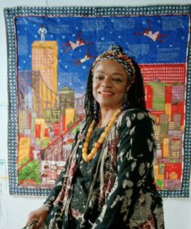 Faith Ringgold's Retrospective Exhibit "American People". image of Faith Ringgold standing before one of her multi-colored tapestries