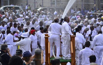 The firehose baptism is a 60-year-old tradition conceived by Harlem's United House of Prayer church . Each summer, women dress in shower caps and white dresses, while men dress in suits and white shirts, and they gather to pray and to be baptized by firehose. the water generates a feeling of exhilaration that can be overwhelming for some people.
