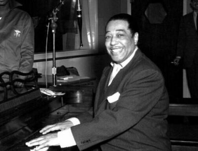 Duke Ellignton sitting at piano smiling