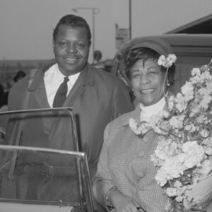 Ella Fitzgerald en Oscar Peterson (links) op Schiphol *24 april 1964 -- By Hugo van Gelderen / Anefo - Nationaal Archief, CC BY 4.0, https://commons.wikimedia.org/w/index.php?curid=46076431